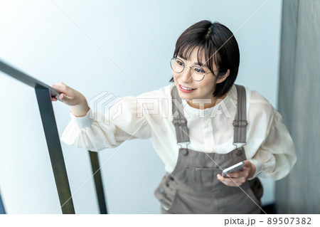 スマホを持って階段をのぼる眼鏡の女性 89507382