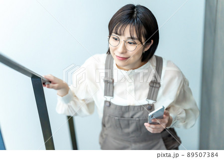 スマホを持って階段をのぼる眼鏡の女性 89507384