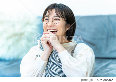 リビングで寛ぐ眼鏡をかけた笑顔の女性 リビングで寛ぐ眼鏡をかけた笑顔の女性 89508502