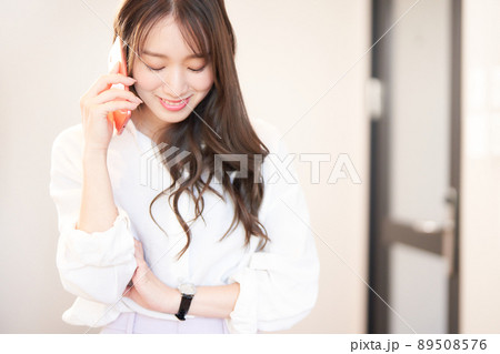 スマホで通話中の笑顔の若い女性 スマホで通話中の笑顔の若い女性 89508576