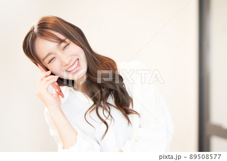 スマホで通話中の笑顔の若い女性 スマホで通話中の笑顔の若い女性 89508577