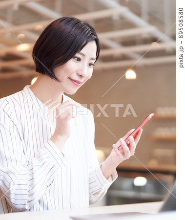 カフェでスマホを使う笑顔の若い女性 89508580