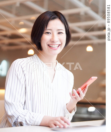 カフェでスマホを使う笑顔の若い女性 カフェでスマホを使う笑顔の若い女性 89508581