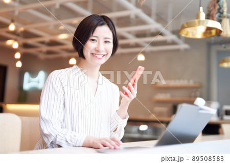 カフェでスマホを使う笑顔の若い女性 カフェでスマホを使う笑顔の若い女性 89508583