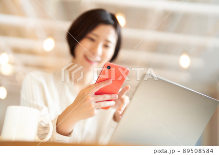 カフェでスマホを使う若い女性の手元 89508584