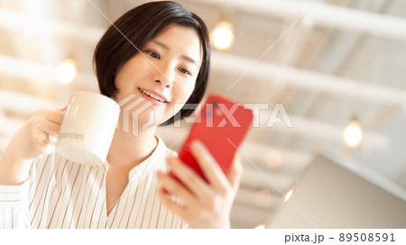カフェでスマホを使う笑顔の若い女性 カフェでスマホを使う笑顔の若い女性 89508591