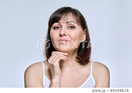 Portrait of middle aged woman looking at camera on light studio background Portrait of middle aged woman looking at camera on light studio background 89508628