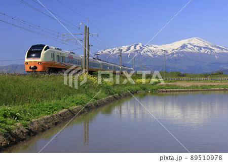 残雪の鳥海山をバックに走る特急いなほ 89510978