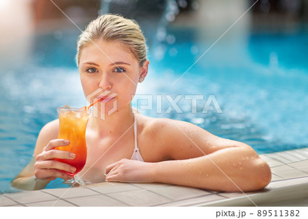 Sipping on the good life. Portrait of a young woman sipping on a cocktail in the pool at a spa. Sipping on the good life. Portrait of a young woman sipping on a cocktail in the pool at a spa. 89511382
