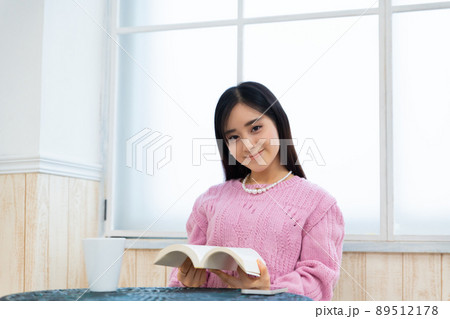 窓辺の席で本を読んでいる若い女性 窓辺の席で本を読んでいる若い女性 89512178