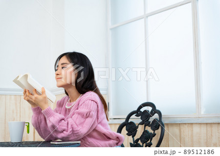 窓辺の席で本を読んでいる若い女性 窓辺の席で本を読んでいる若い女性 89512186