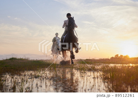 Horses lend us the wings we lack. Shot of two young women riding their horses outside on a field. 89512261