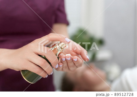 Masseur applies the oil to the hands to perform the massage. Cosmetologist treats the hands before the procedure. Close up. 89512728