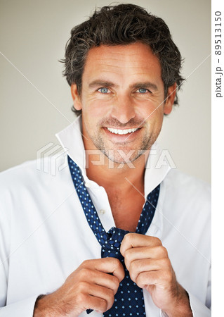Man wearing tie. Closeup of mature man knotting tie and giving you an attractive smile. Man wearing tie. Closeup of mature man knotting tie and giving you an attractive smile. 89513150