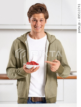 Are these juicy berries all for me. A handsome young man pointing to a bowl of raspberries. 89513741