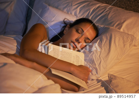 She fell asleep reading again. Shot of an attractive young woman sleeping holding book. She fell asleep reading again. Shot of an attractive young woman sleeping holding book. 89514957