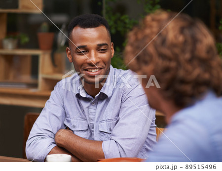 Catching up with an old friend. A handsome young man sitting with a friend at a cafe. Catching up with an old friend. A handsome young man sitting with a friend at a cafe. 89515496