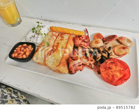 Traditional English Big Breakfast with poached egg, sausage, bacon, tomatos, hash brown, mushroom, and baked beans Traditional English Big Breakfast with poached egg, sausage, bacon, tomatos, hash brown, mushroom, and baked beans 89515782