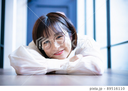 フローリングに寝転んでくつろぐ眼鏡の女性 フローリングに寝転んでくつろぐ眼鏡の女性 89516110