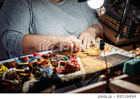Senior elderly female hands embroider choose cotton craft threads. Handmade cross stitch embroidery in women s hands. Cross stich set in process Senior elderly female hands embroider choose cotton craft threads. Handmade cross stitch embroidery in women s hands. Cross stich set in process 89516684