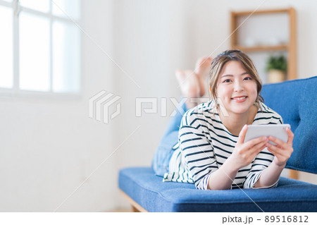 ソファーでスマホをする若い女性。 ソファーでスマホをする若い女性。 89516812