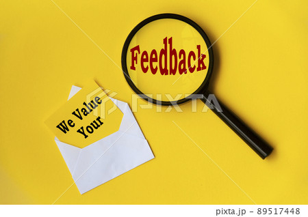 Top view of text - we value your feedback on notepad and magnifying glass. Conceptual 89517448