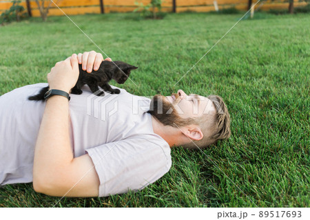 Man with little kitten lying and playing on grass - friendship love animals and pet owner concept Man with little kitten lying and playing on grass - friendship love animals and pet owner concept 89517693