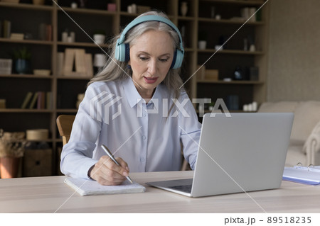 Focused older student in wireless headphones watching virtual workshop 89518235