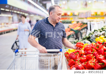 elderly retired man buying bell pepper in grocery section of supermarket 89519322