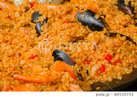 Orange paella with shrimp, mussel, rice, spice, saffron in huge paella pan 89520743