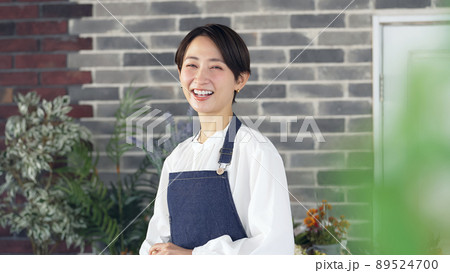 出迎えるエプロンをつけた女性　店員　接客 89524700