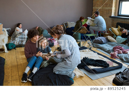 Healthcare worker giving medical help to young female refugee and little boy 89525245