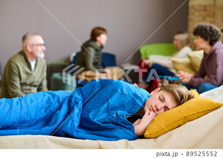 Cute serene boy with his head on pillow sleeping under blanket on couchette Cute serene boy with his head on pillow sleeping under blanket on couchette 89525552
