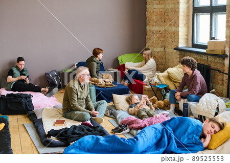 Young woman talking to mature man while both sitting on sleeping places Young woman talking to mature man while both sitting on sleeping places 89525553