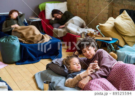 Cute boy with smartphone and his mother looking at screen while resting in bed 89525594