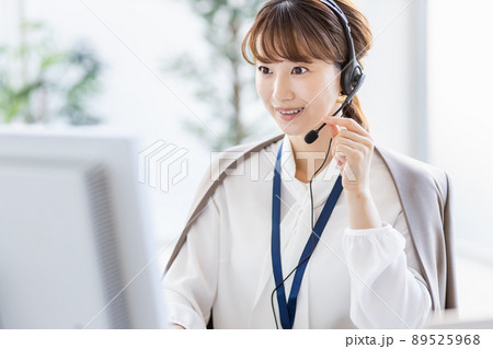 パソコンの前でヘッドセットをつけて通話をしているビジネスウーマン 89525968