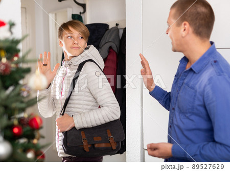 Guy saying goodbye father in entrance hall of apartment after christmas Guy saying goodbye father in entrance hall of apartment after christmas 89527629