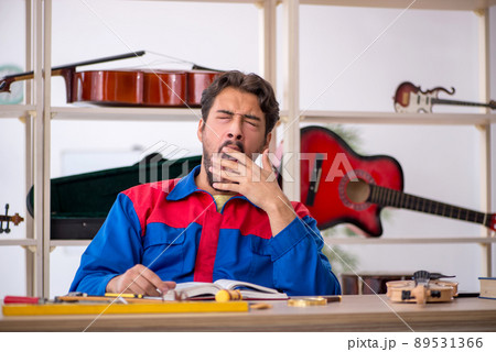 Young man repairing musical instruments at workshop Young man repairing musical instruments at workshop 89531366