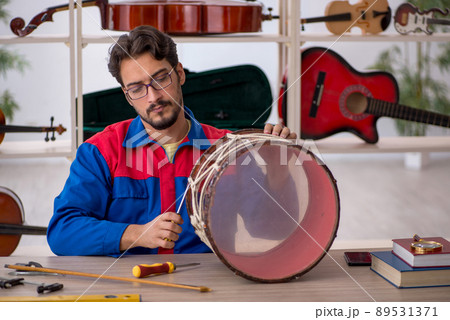 Young man repairing musical instruments at workshop 89531371
