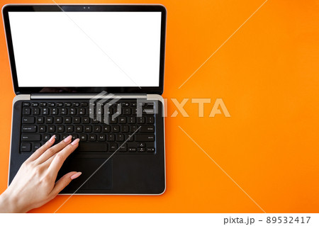 Online education. Digital technology. Advertising background. Unrecognizable woman typing laptop with blank screen isolated orange copy space. 89532417