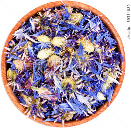 Dried cornflower tea in a small wooden bow isolated. Dried cornflower tea in a small wooden bow isolated. 89534089