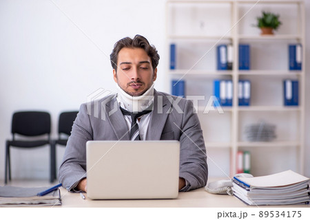 Young male employee after car accident working in the office Young male employee after car accident working in the office 89534175