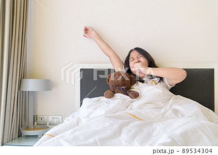Portrait of asian girl awaking, wake up on the bed. cute asian girl stretching her arms. Portrait of asian girl awaking, wake up on the bed. cute asian girl stretching her arms. 89534304