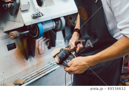 Close-up of cobbler working on pair of shoes with machine 89536632