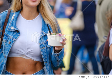 Crop woman with takeaway salad walking on street Crop woman with takeaway salad walking on street 89537317