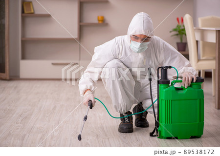 Young male contractor doing pest control at home 89538172