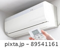白色のエアコンとリモコン操作をする手 89541161