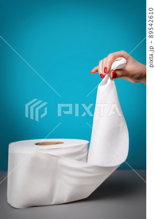 Women's hands with red manicure, carefully holding the edge of toilet paper. Turquoise background. Copy space. Concept of coronovirus, panic shopping and hygiene 89542610