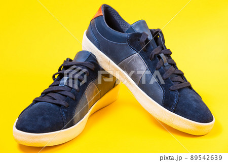 Male's new sneakers made of blue leather beautifully laid out on a yellow background. Close up Male's new sneakers made of blue leather beautifully laid out on a yellow background. Close up 89542639