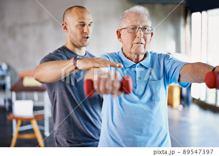 Rehabilitation is never easy. Shot of a physiotherapist helping a senior man with weights. 89547397
